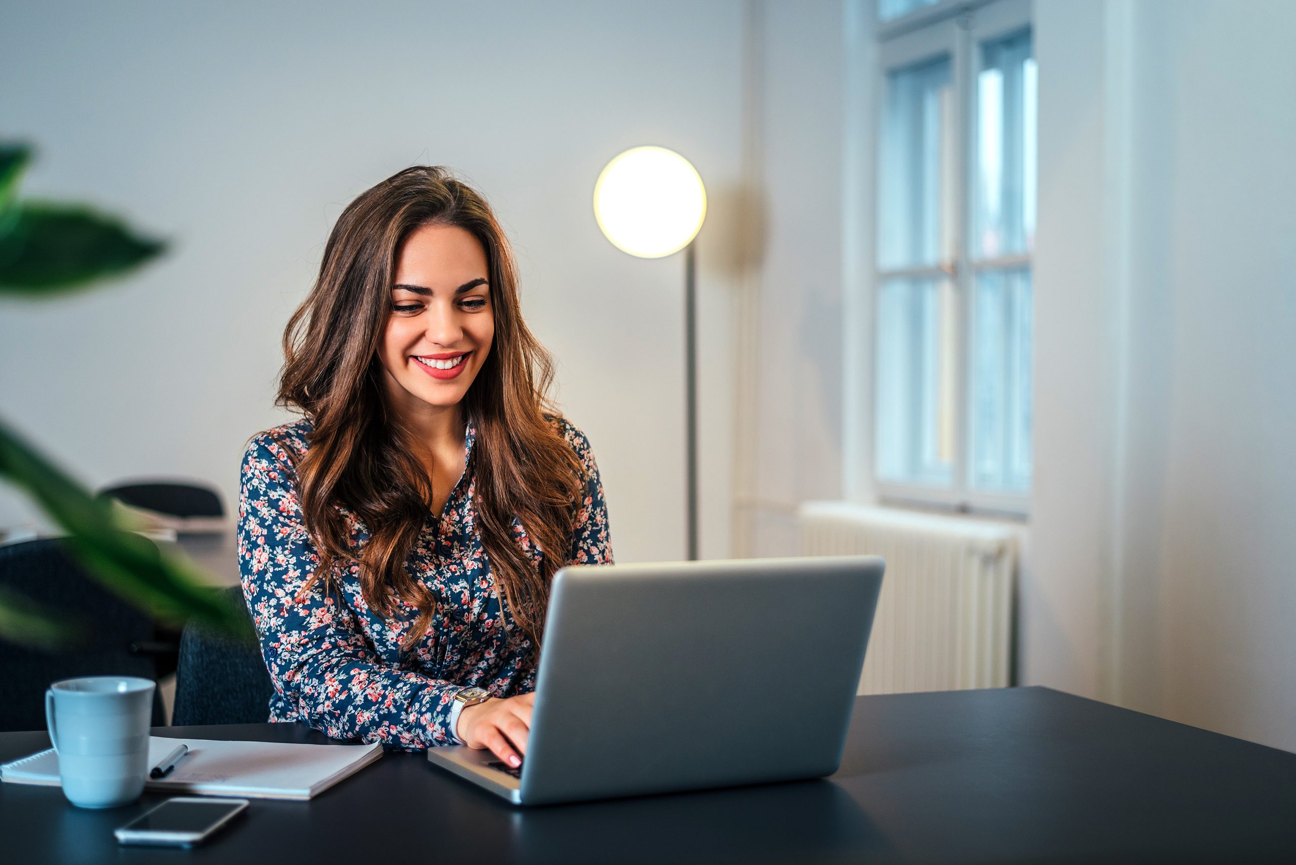 An admissions advisor smiles as she types a follow-up on her laptop