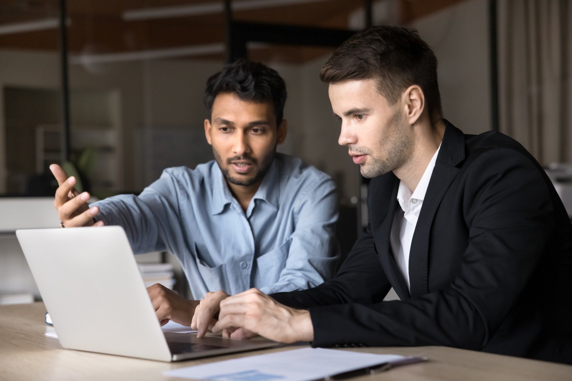 An admissions director reviews an interview scorecard on a laptop with an advisor