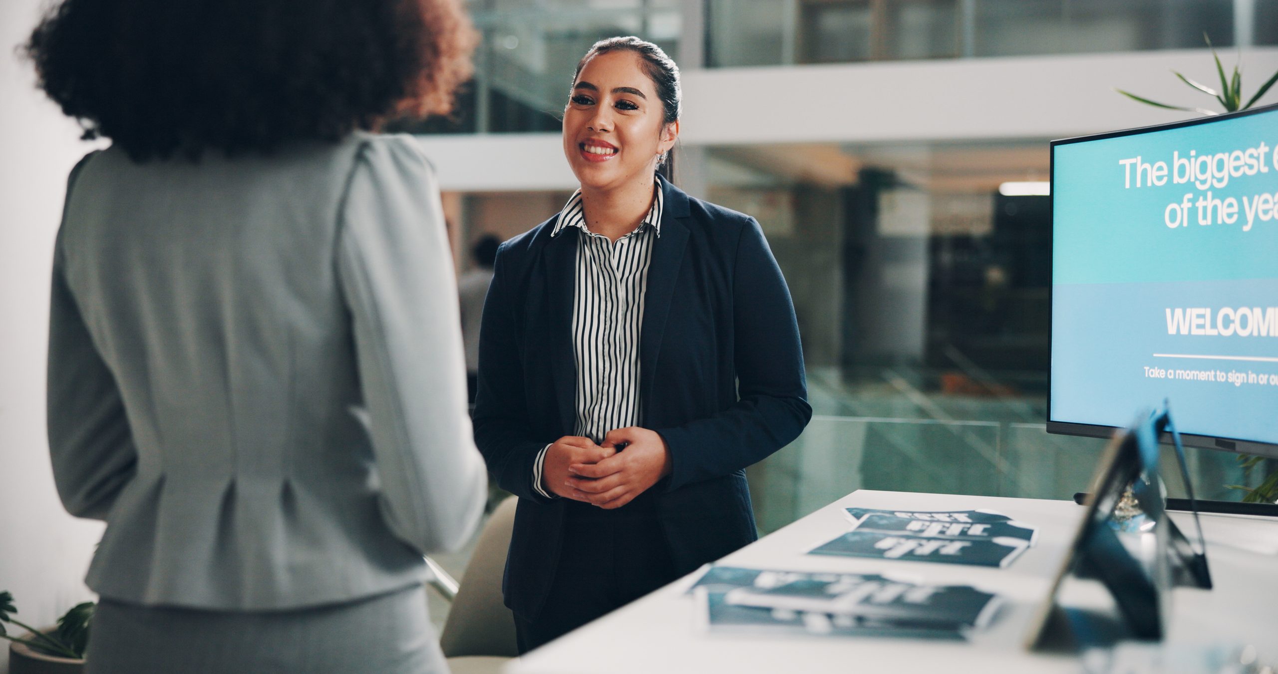 A sales rep greets a visitor at a trade show booth
